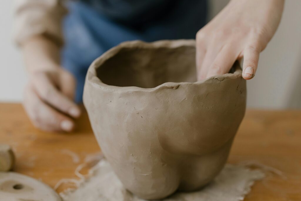 Close-up of hands crafting a clay pot in an artisan workshop, showcasing the art of pottery making.
